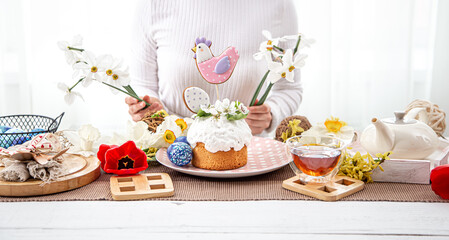 A woman decorates a festive table with flowers for the celebration of Easter.