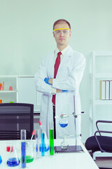 male scientist performs an experiment on chemical test tube in a laboratory wearing blue gloves and safety glasses