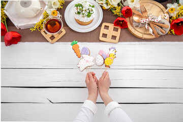 Festive Easter gingerbread cookies on wooden sticks in female hands top view.