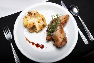 Presentación plato Solomillo a las finas hierbas con  papas a la crema & copa de vino tinto sobre mesa