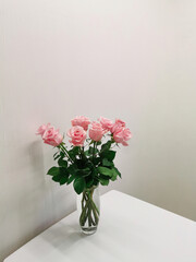Bouquet in a vase of pink roses on a table in a minimalist white kitchen. Floristics and minimalism in the interior.