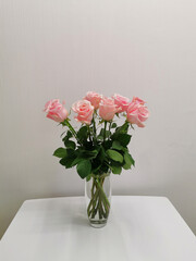 Bouquet in a vase of pink roses on a table in a minimalist white kitchen. Floristics and minimalism in the interior.