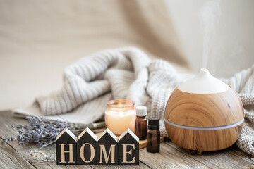 A cozy home composition with an air humidifier, a set of aromatic oils and the decorative word home.