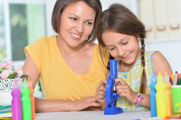 Mother teaching her daughter to use microscope