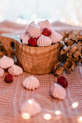 Still life photo of pink raspberry Meringue Cookies in a traditional Finnish kuksa cup. Dry hydrangeas and bokeh lights in the foreground, and bokeh bubbles in the background.