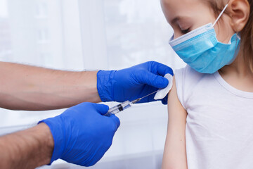 A doctor injects a vaccination into the hand of a little baby girl, a healthy and medical concept. Coronavirus, treatment