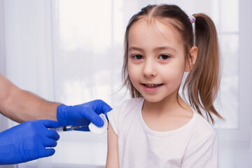 A doctor injects a vaccination into the hand of a little baby girl, a healthy and medical concept. Coronavirus, treatment