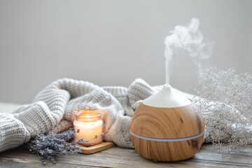 Cozy home composition with air humidifier, knitted element, lavender and candle copy space. - obrazy, fototapety, plakaty