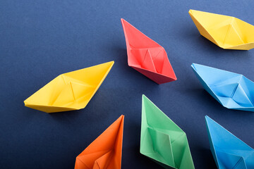 A group of colored paper boats in deep blue. Concept of teamwork, leadership.