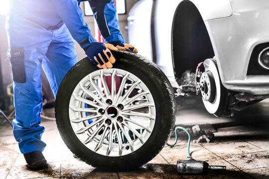 Auto Mechanic Working In Garage And Changing Wheel Alloy Tire.