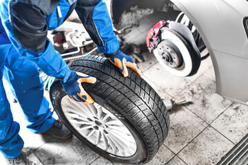 Auto mechanic working in garage and changing wheel alloy tire.