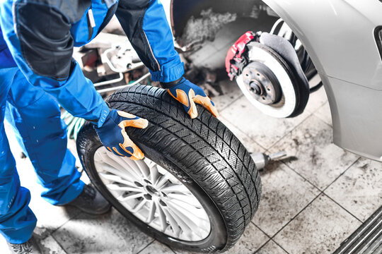 Auto mechanic working in garage and changing wheel alloy tire.
