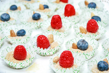 dessert with coconut, ripe berries, almonds, raspberries and blueberries. In a white paper wrapper with green hearts