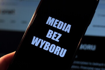 Media blackout protest in Poland. A person is holding a smartphone with the sign “Media bez wyboru” (Eng. Media without a choice) in front of a black TV screen. - obrazy, fototapety, plakaty