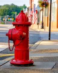 Tight view of a fire hydrant on a small town street with American flags in the background.