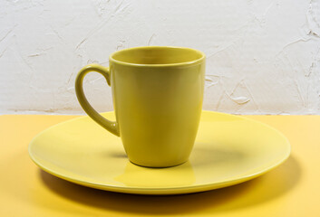 an empty yellow plate and cup on a yellow and white textured background