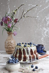 Chocolate Bundt Cake with blueberries and white icing and pistachios.