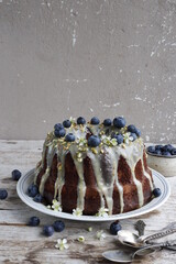 Chocolate Bundt Cake with blueberries and white icing and pistachios.