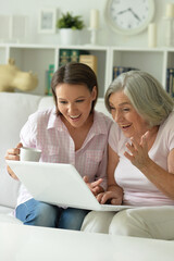 Fototapeta premium mother and daughter sitting at table with laptop, at home
