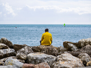 Hombre pensativo mirando el mar desde el muelle del puerto