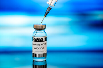 Vaccination. Bottle with vaccine and syringe in front of blue background. Medicine and healthcare...