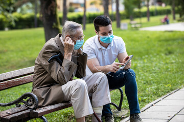 Grandfather and grandson listen to music and enjoy the park