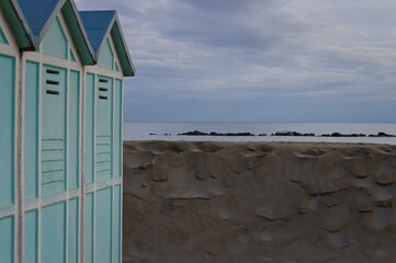 A sand dune near blue beach sheds on the Mediterranean sea coast (Pesaro, Italy, Europe)