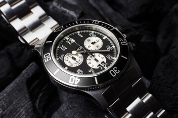 Black luxury watch on black coals background