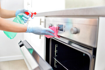 Woman in gloves cleaning kitchen.	