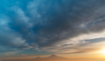 Fototapeta na wymiar Beautiful sunset with dramatic orange clouds. The mountains in a clouds and fog. Ararat mountain.