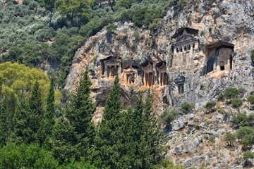 Fototapeta na wymiar Amazing view of the Lycian tombs carved into the rock on the Dalyan River, ancient Caunos town, Turkey, Mugla. Turkish famous historical landmark