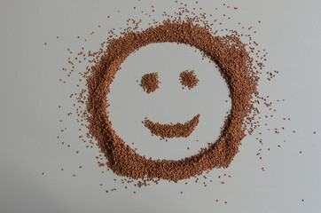 Smiley face made out of brown seeds on white background