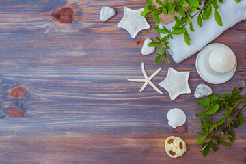 Flat lay spa composition with branches with green leaves, sea salt in bowl, towels on wooden background