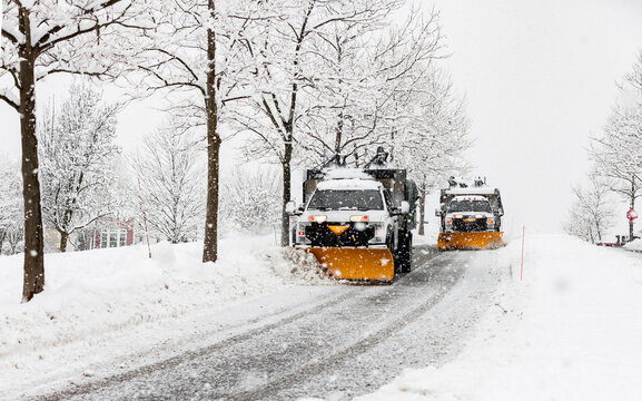 snow plowing machine in suburban neighborhood during northeastern storm nor'easter