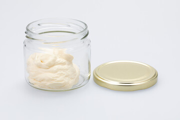 Glass jar with sweet vanilla cream on white
