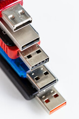 Five colorful usb flash drives on top of one another, against a white background