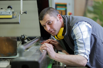 metalworker operating tool machine in manufacturing workshop