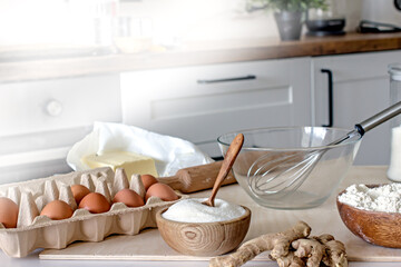White kitchen table with ingredients and accessories for homemade baked goods. Flour, sugar, eggs,...