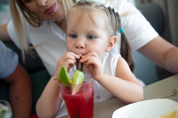 Family with kid resting in the cafe and drinking juice