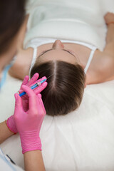 Vertical shot of a woman getting hairloss treatment injections by cosmetician