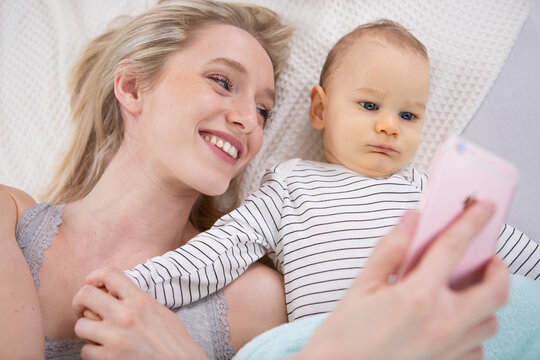 woman with a baby doing a selfie lying