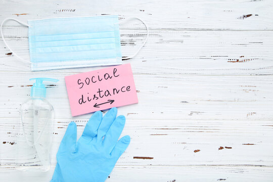 Inscription Social Distance with medicine mask, gloves and sanitizer bottle on white background - Powered by Adobe