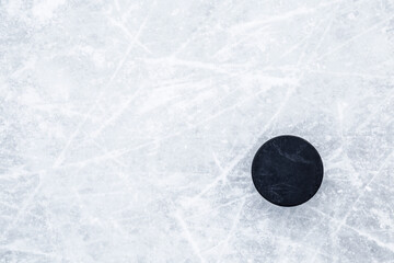 Black old rubber puck on ice background. Closeup. Empty place for text. Top down view. - obrazy, fototapety, plakaty