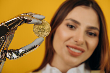 Portrait of a beautiful young woman with a silver bionic prosthetic arm holding a bitcoin coin in...