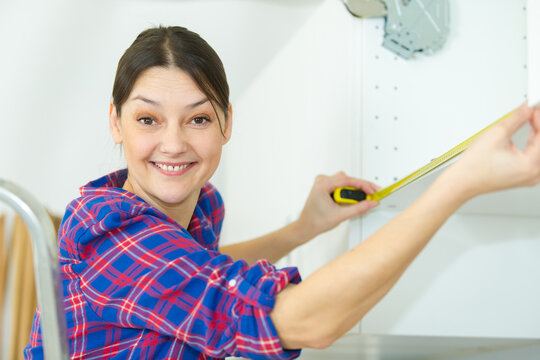 female carpenter measuring a cupboard