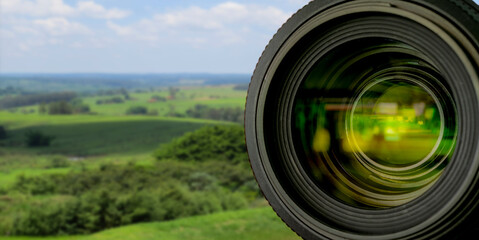 reflection in the lens of the photo camera with blurred landscape background. selective focus.