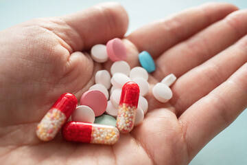 Close-up colorful pills and capsules in a person's hand on a blue background
