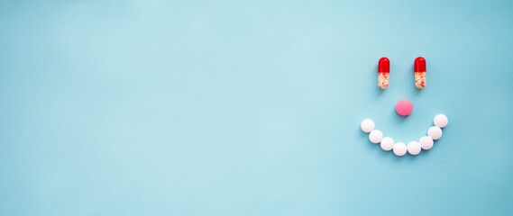 Happy smile face from tablets, pills and capsules on a blue background with copy space banner