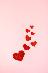 Vertical Valentine background with red glitter handmade hearts on pink background. Love, romantic concept vertical for social media