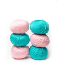 Pink and green skeins of wool yarn on a white insulated background.